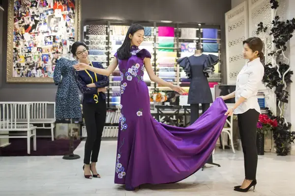 Fashion designers examining a dress on a client
