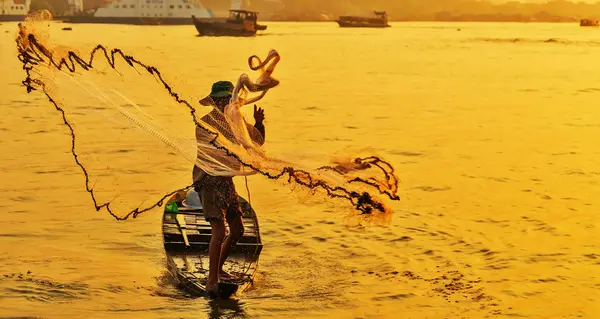 Fisherman casting a net during sunset