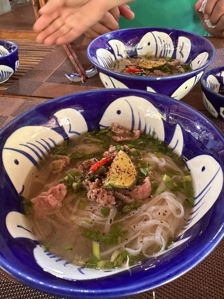 Instructor garnishing bowls of beef noodle soup